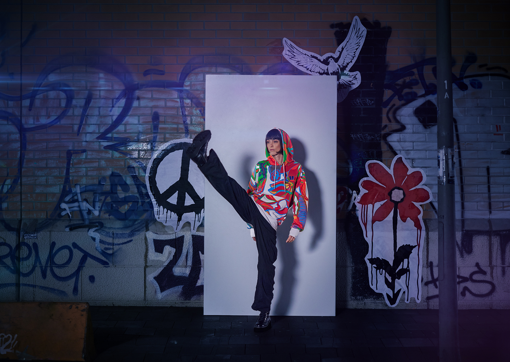 Frau steht vor einer Graffiti Wand und trägt den 17 Ziele Hoodie