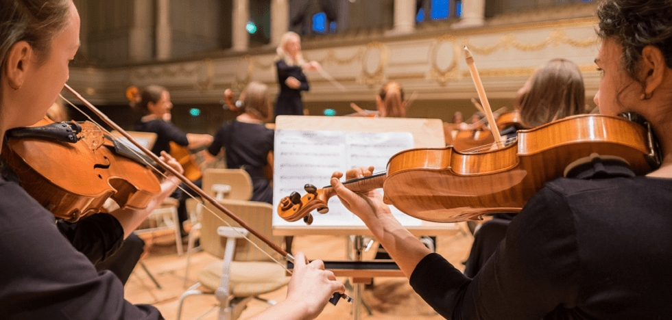 Zwei Musikerinnen spielen Geige in einem Orchester